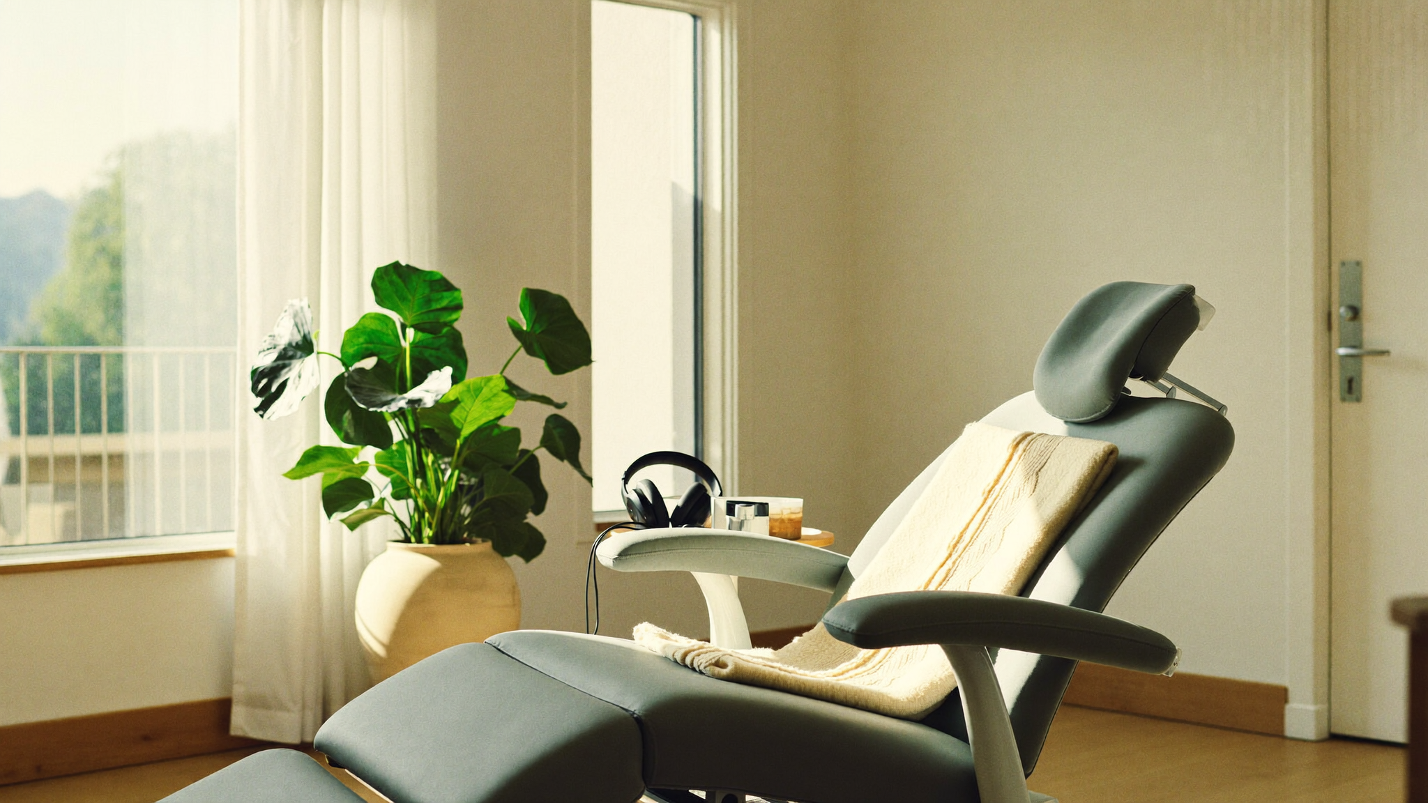 An empty, softly lit dental treatment room with a folded blanket and headphones on the chair, set up to feel calm rather than clinical